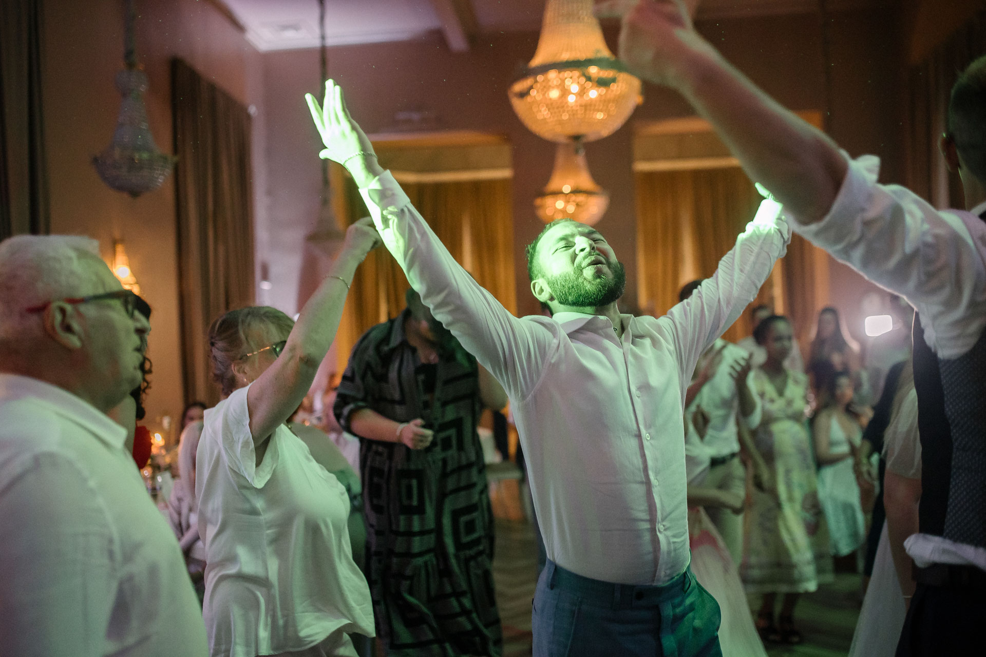 Invités dansant avec énergie, bras levés, sous les lumières colorées de la soirée
