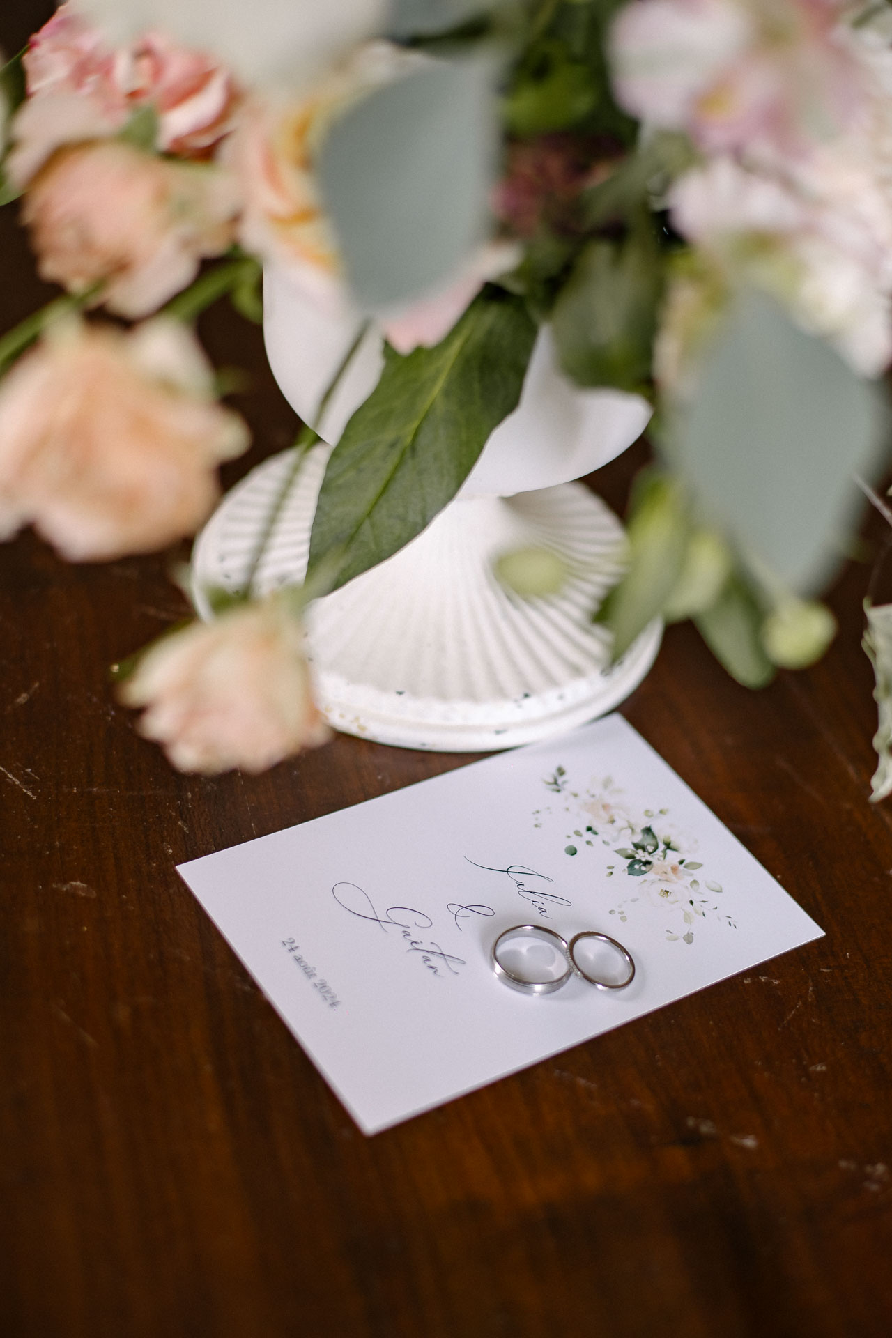Alliances posées près du bouquet de la mariée et du faire-part illustré