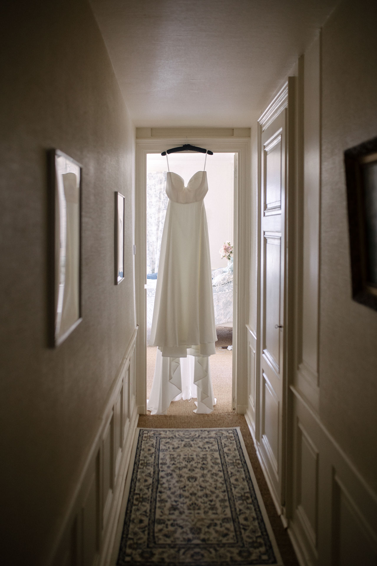La robe de mariée suspendue dans le couloir, prête pour le grand jour
