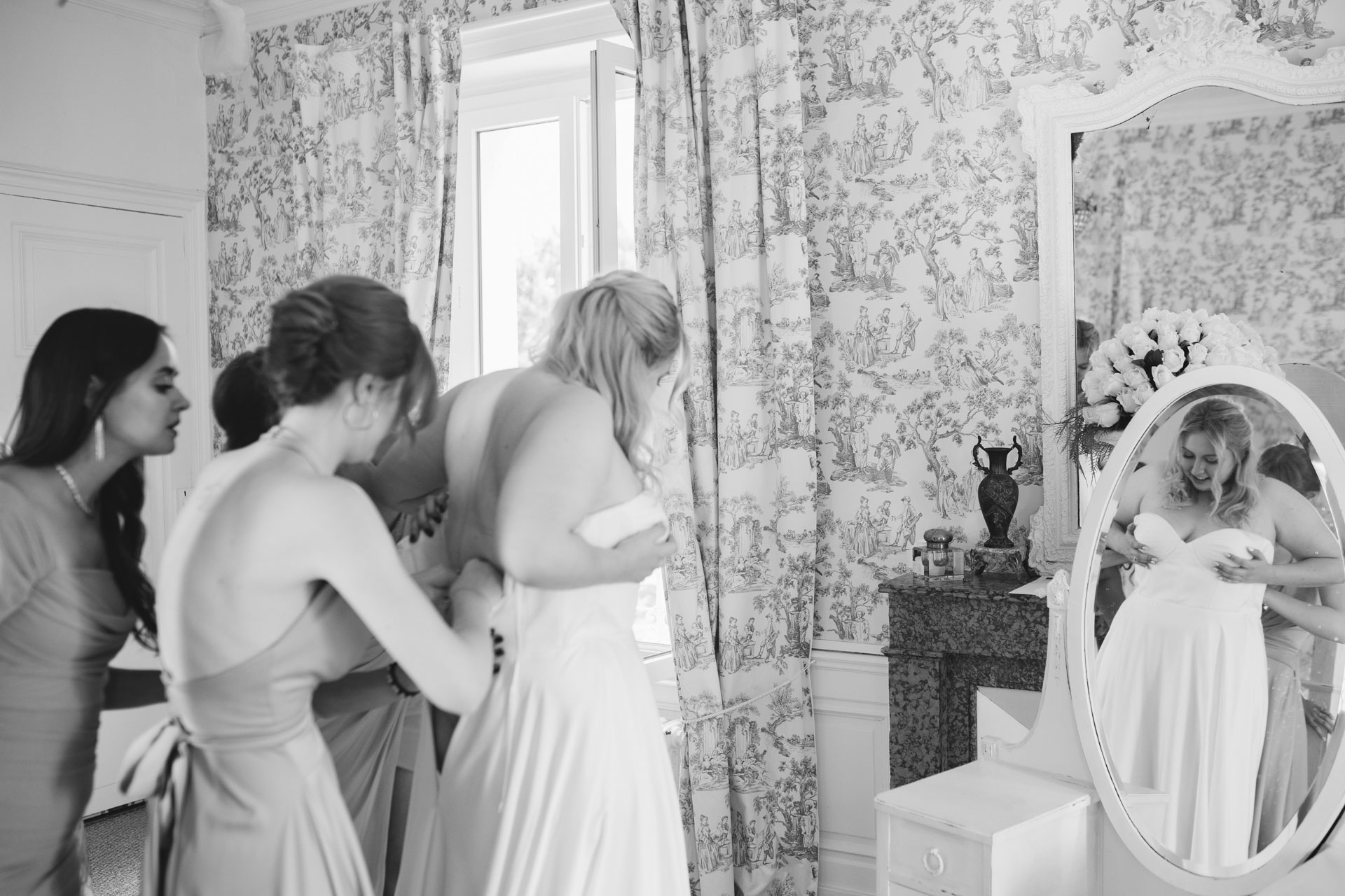 Ajustement de la robe de la mariée par les témoins dans la lumière du matin