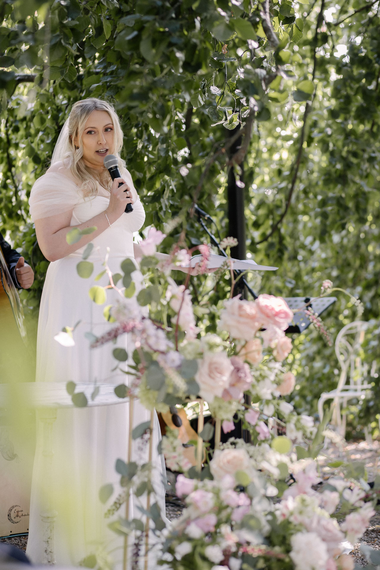 La mariée prononçant un discours émouvant, entourée de fleurs roses et blanches