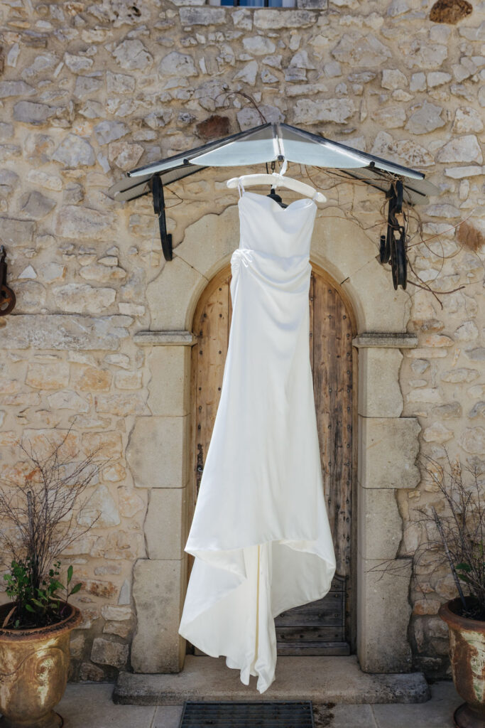 Bride's wedding gown hanging in a stone doorway — Grange de Javon, Provence