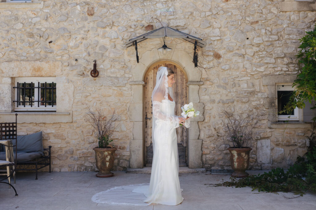 Bride portrait with bouquet against a Provence stone facade — Grange de Javon wedding