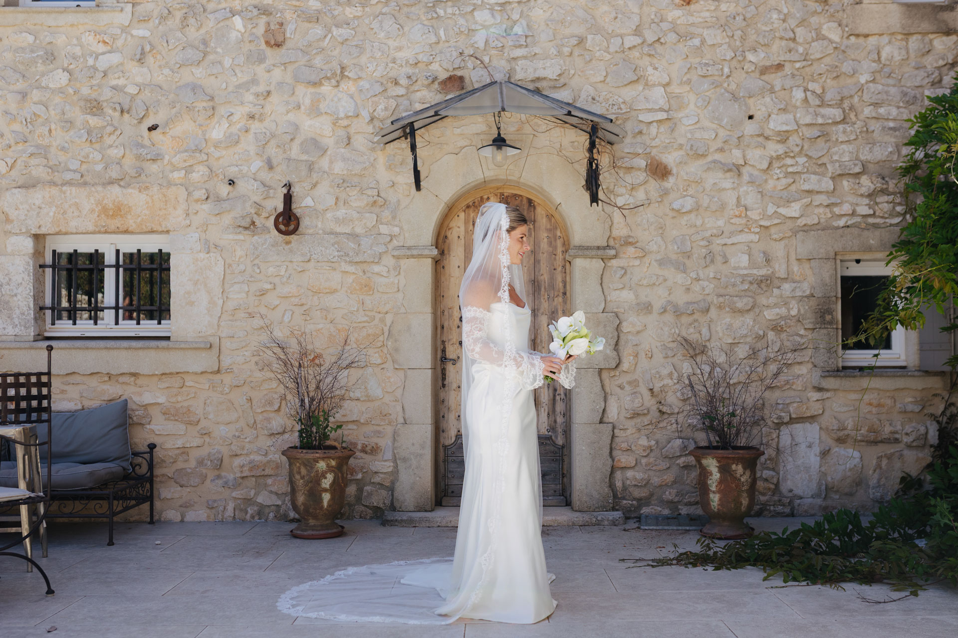Bride portrait with bouquet against a Provence stone facade — Grange de Javon wedding