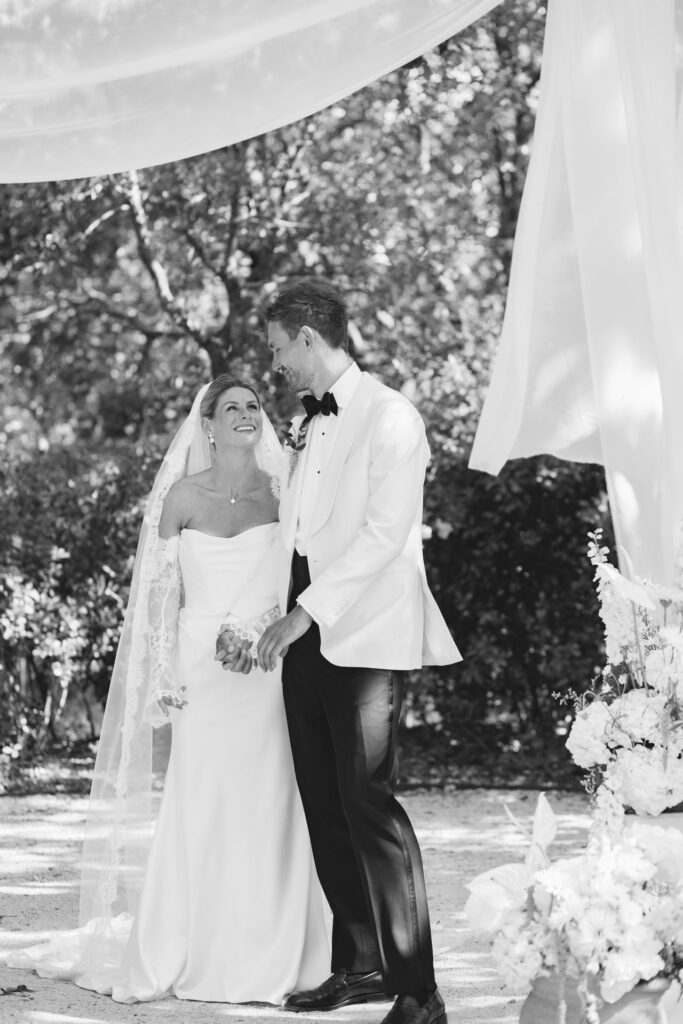 First kiss under the ceremony arch, black and white — Grange de Javon wedding