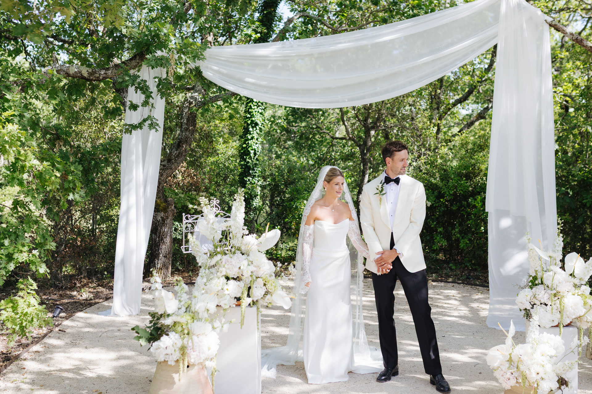 Bride and groom beneath the floral ceremony arch — Grange de Javon wedding