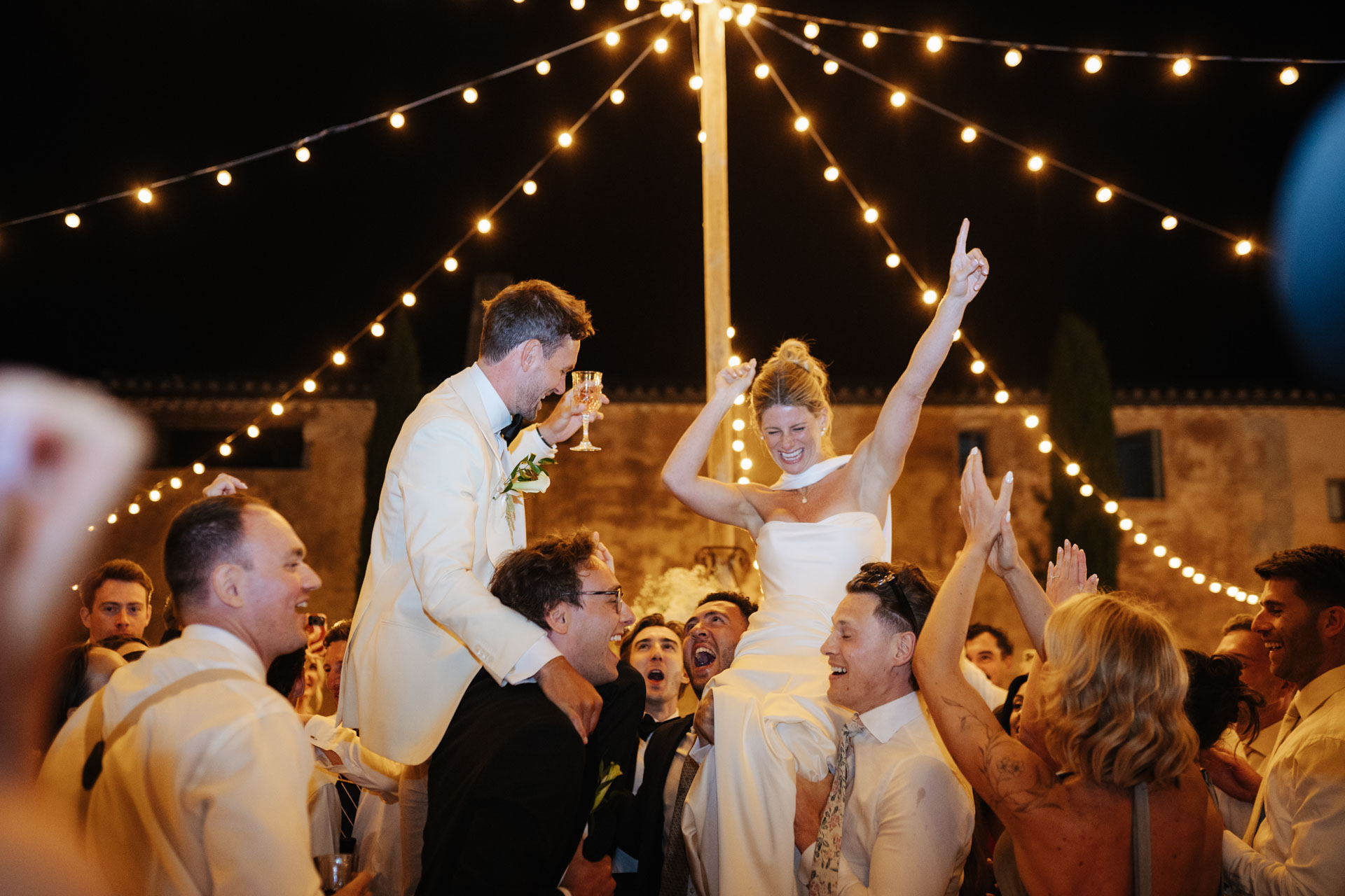 Bride cheering on the dance floor under string lights — Grange de Javon, Provence