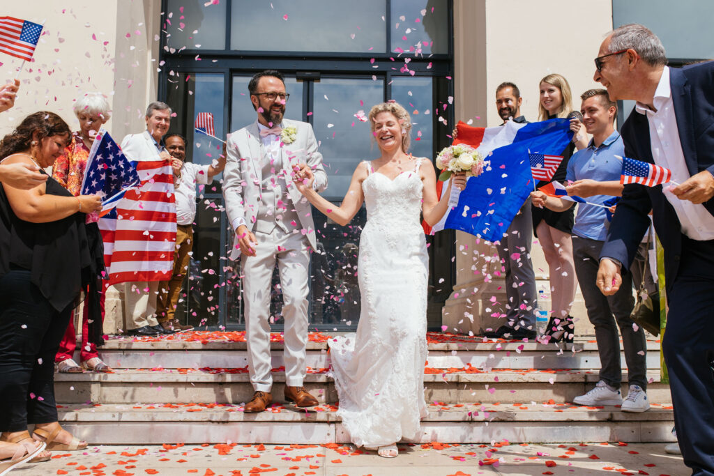 Mariés accueillis par leurs invités sous une pluie de confettis et de drapeaux