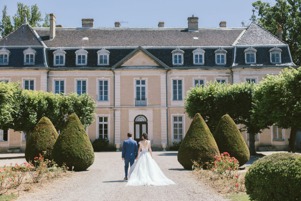 Couple de mariés marchant main dans la main vers un château