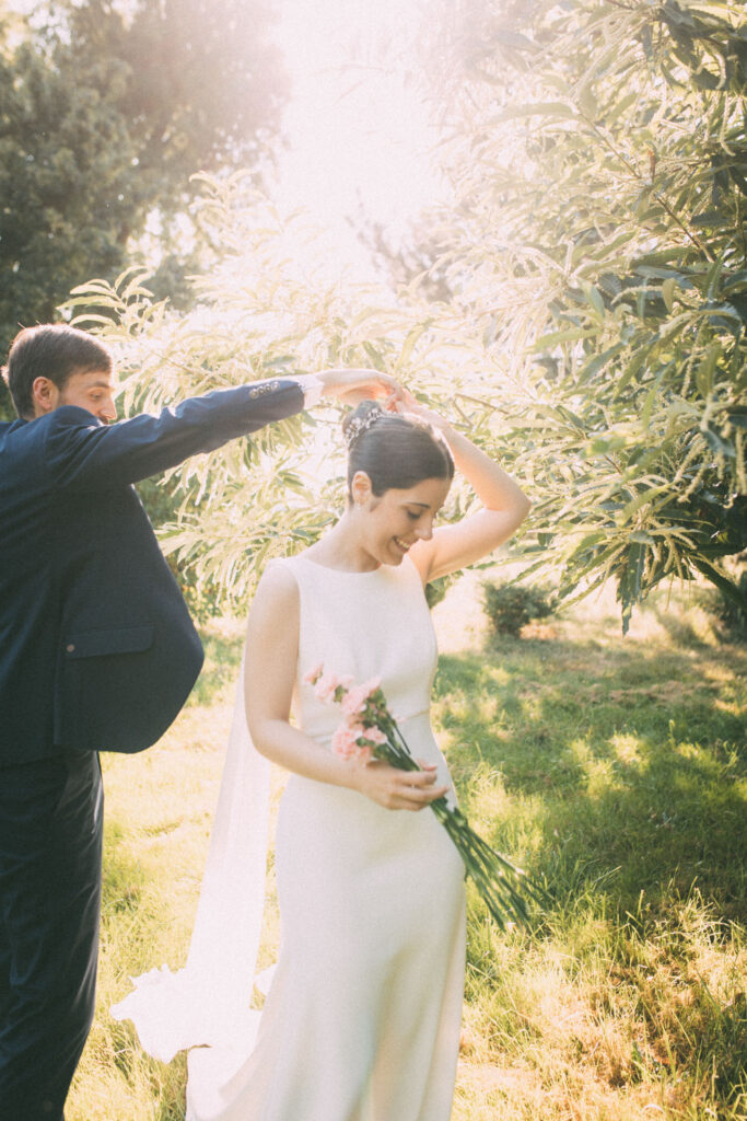 Marié posant une couronne de fleurs sur la tête de la mariée sous les arbres