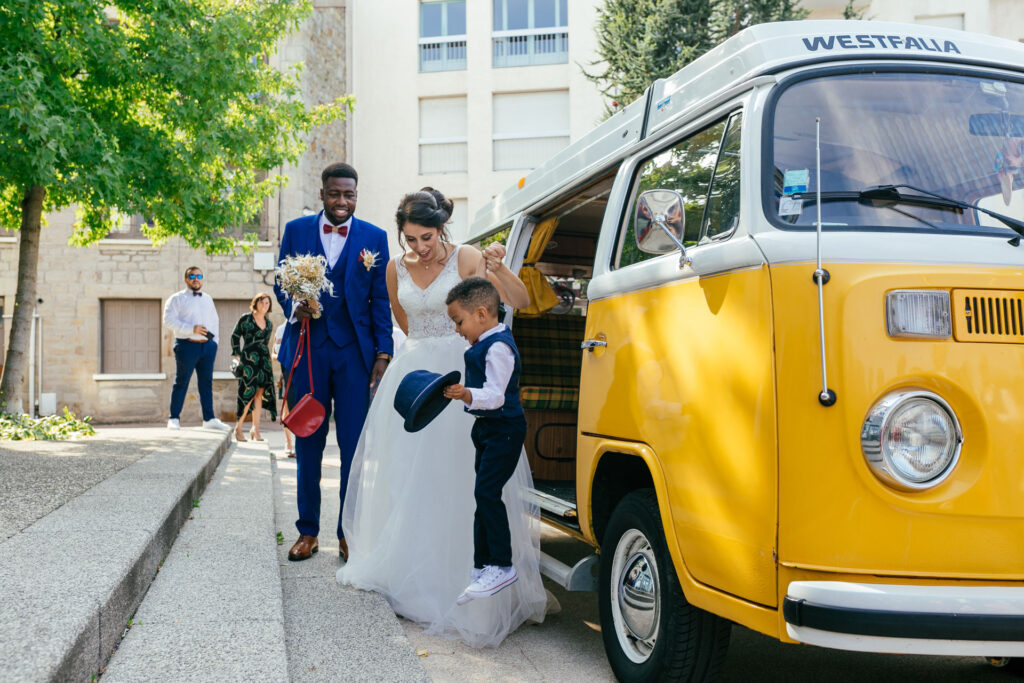 Mariés souriants près d'un combi Volkswagen jaune