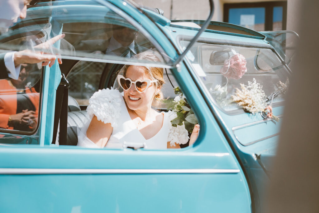 Mariée souriante dans une voiture vintage bleue