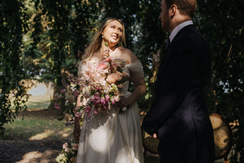 Mariée tenant son bouquet, regard tourné vers le marié