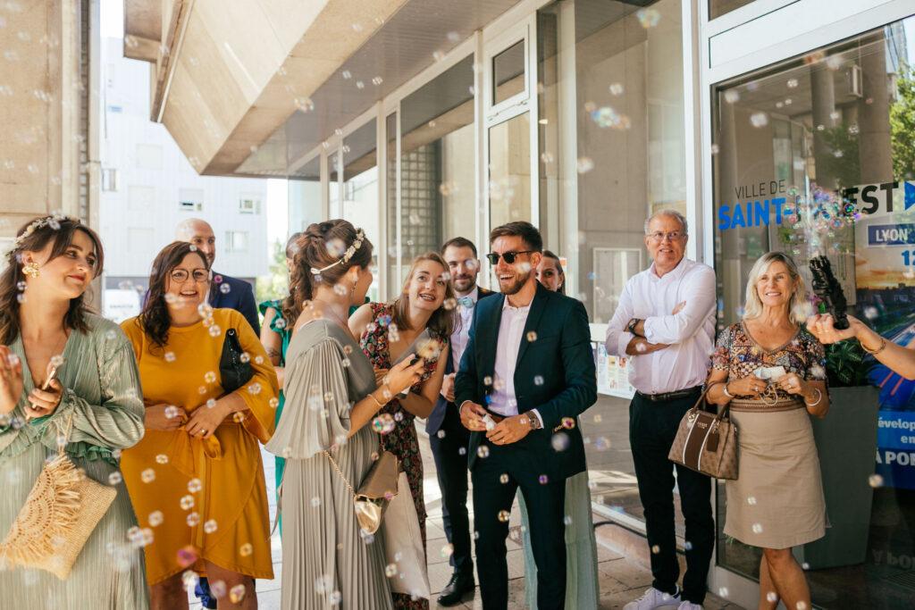 Mariés et invités fêtant la sortie de mairie avec des bulles de savon