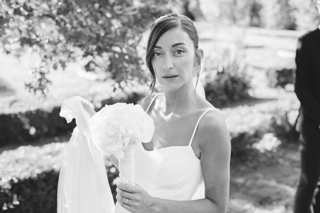 Portrait de mariée au bouquet blanc, lumière naturelle dans un jardin