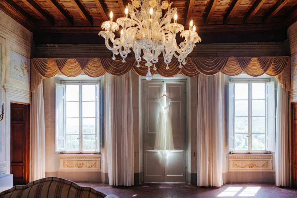 Wedding dress hanging by a window at Villa Buonvisi, Tuscany