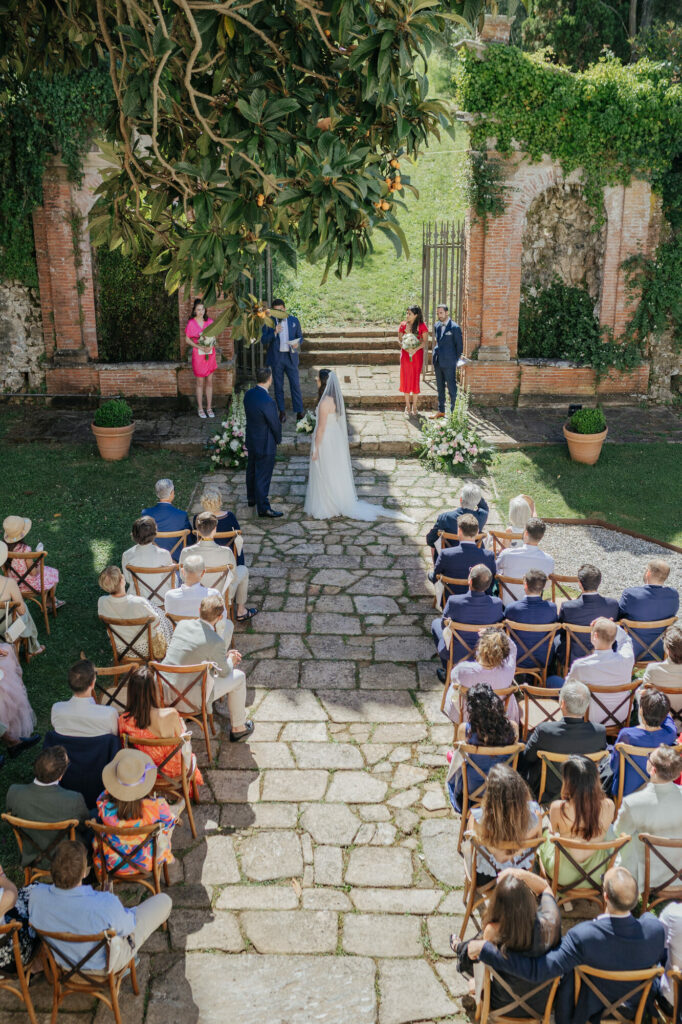 Wedding ceremony beneath the ruined brick arches at Villa Buonvisi, facing the olive grove