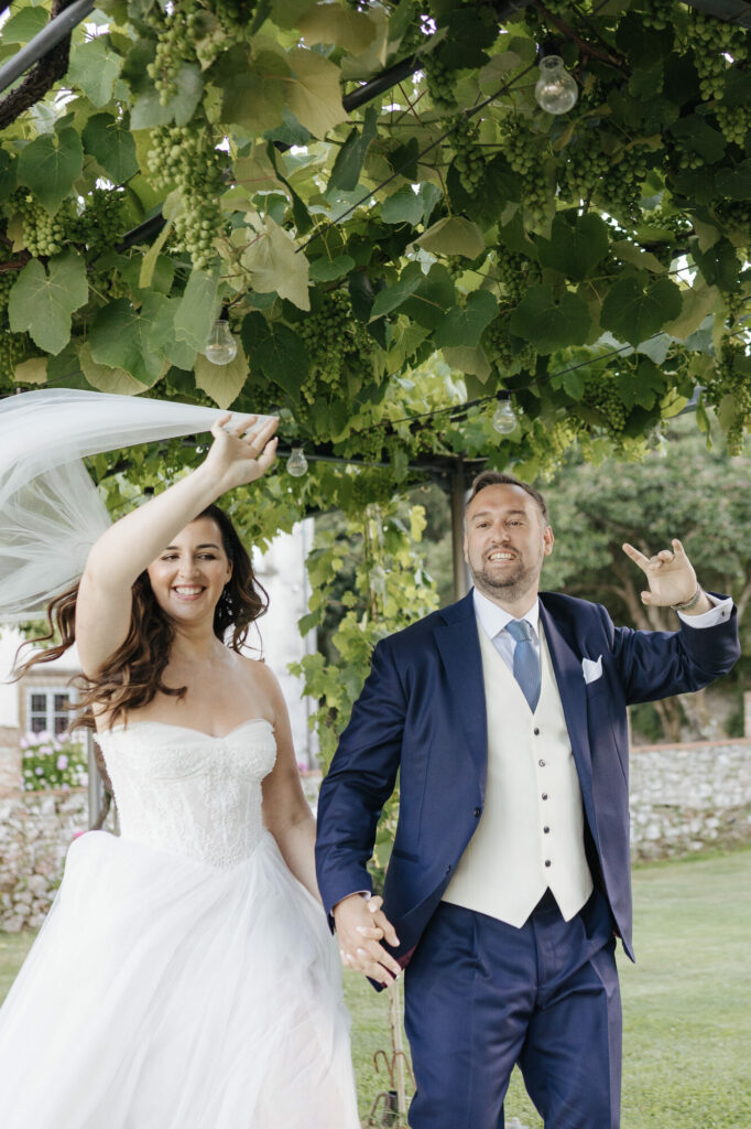 The bride's veil catches the wind as the couple laughs