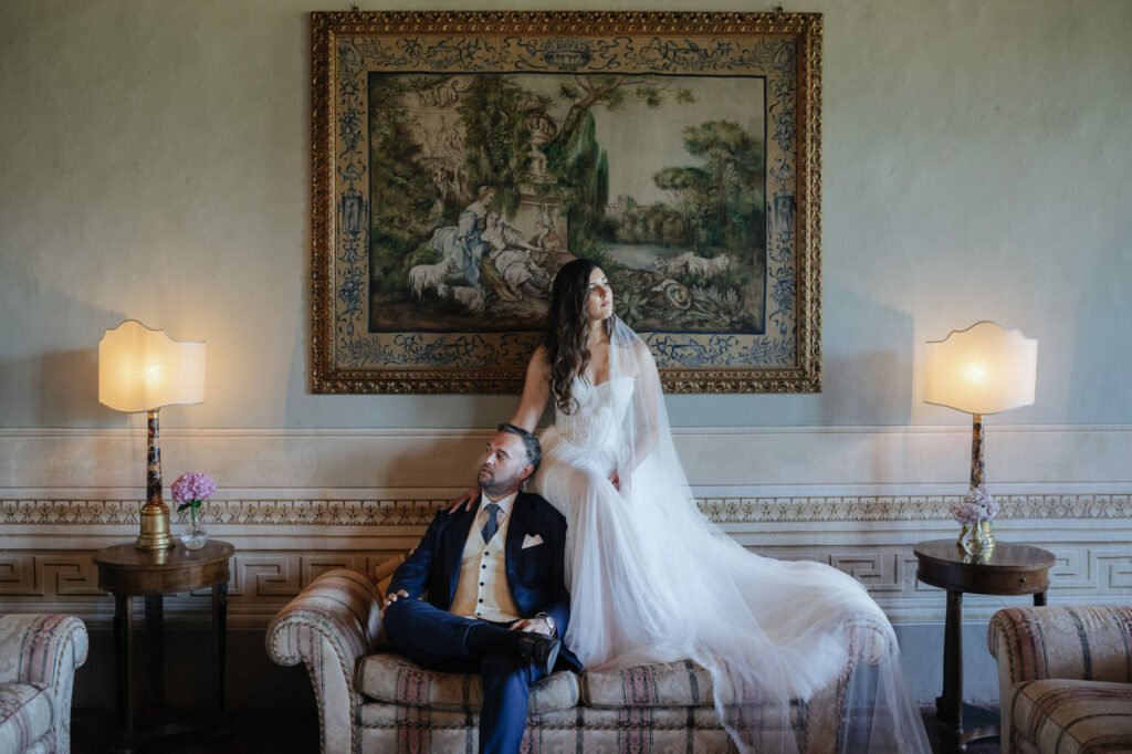 Portrait of the couple beneath an antique tapestry at Villa Buonvisi